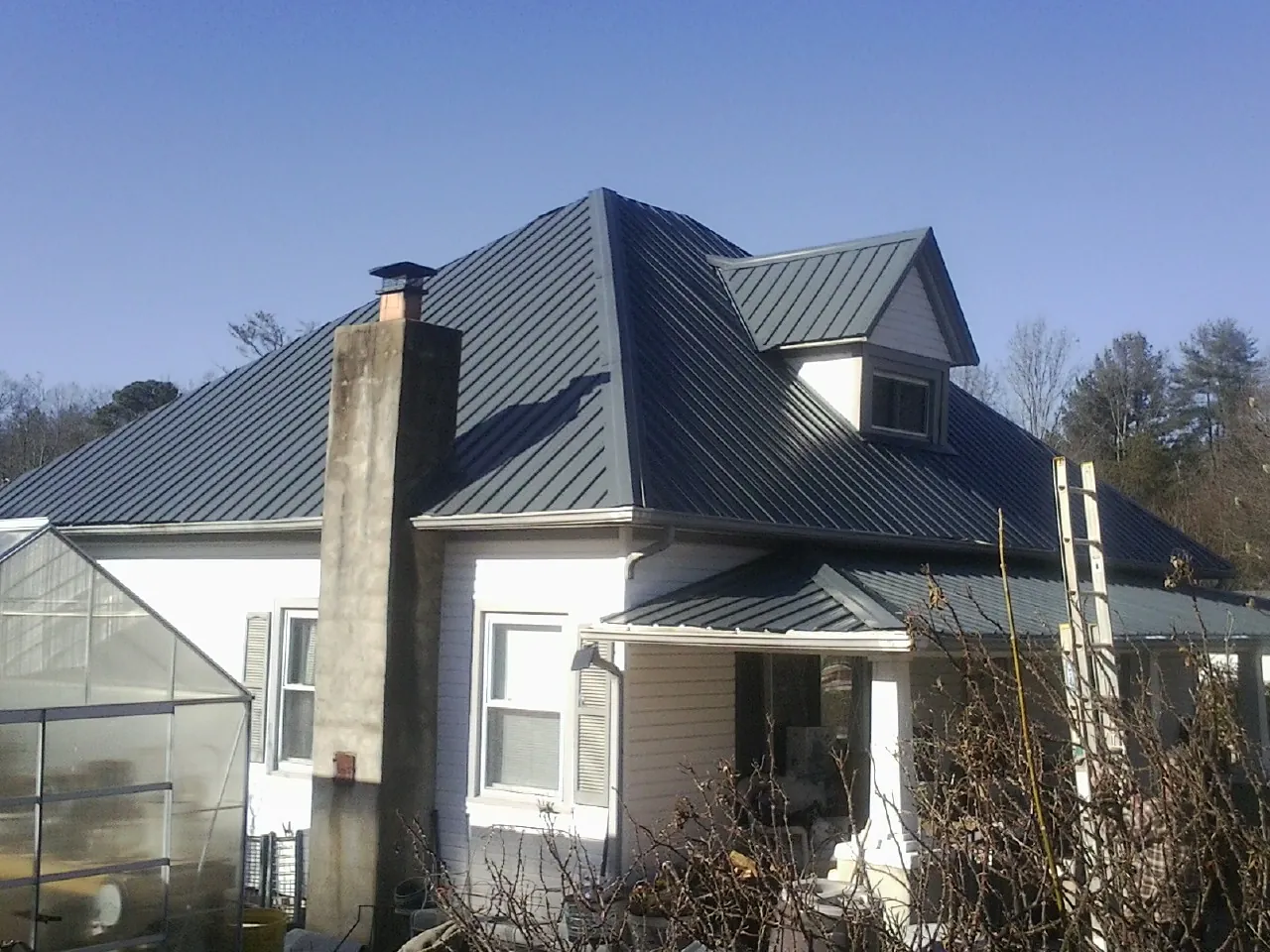 Dark blue standing seam metal roof on a white farmhouse with dormer — Slate & Tile Roof Repair by Roofing Brothers in Mokena