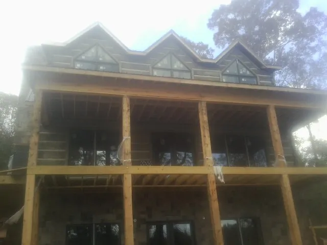 Dormers and porch framing on a large log home under construction — Roof Coating work by our crew in Mokena