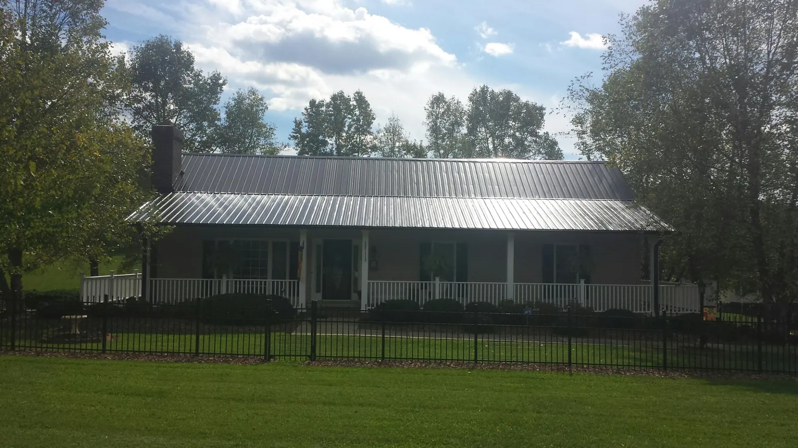 Gray metal roof on a brick ranch with a full width front porch — Gutter Guard Installation work by our crew in Mokena