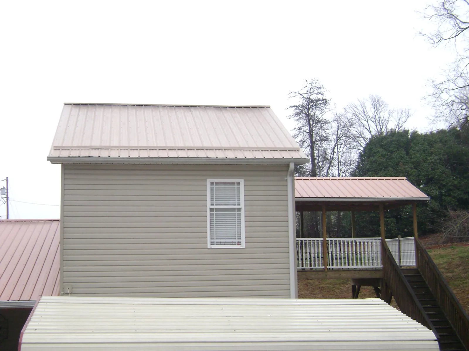 Tan metal roofs on a two story addition and attached porch, from a Roof Replacement job in Mokena